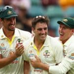 BRISBANE, AUSTRALIA - DECEMBER 08: Australian captain Pat Cummins celebrates with team mates after dismissing Chris Woakes of England during day one of the First Test Match in the Ashes series between Australia and England at The Gabba on December 08, 2021 in Brisbane, Australia. (Photo by Chris Hyde/Getty Images)