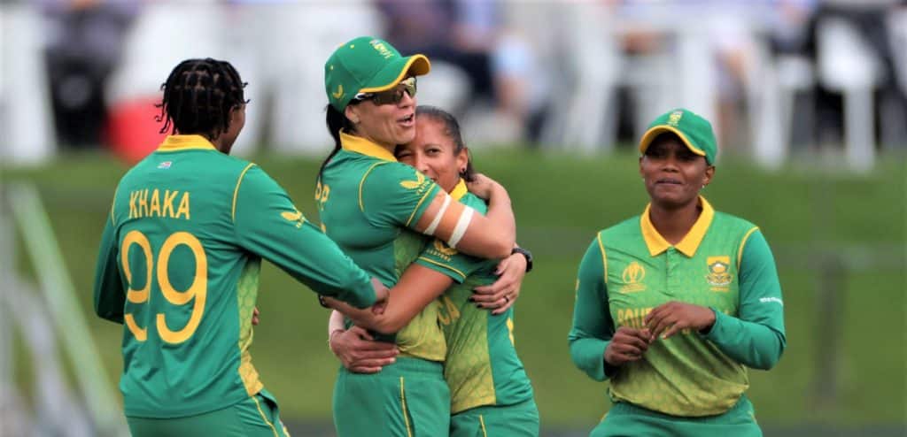 CHRISTCHURCH, NEW ZEALAND - MARCH 31: Marizanne Kapp, left, and Shabnim Ismail from South Africa hug as team mates Ayabonga Khaka, left, and Masabata Klaas right, arrive to celebrate after Kapp caught Natalie Sciver from England off the bowling of Ismail during the 2022 ICC Women's Cricket World Cup Semi Final match between South Africa and England at Hagley Oval on March 31, 2022 in Christchurch, New Zealand. (Photo by Peter Meecham/Getty Images)